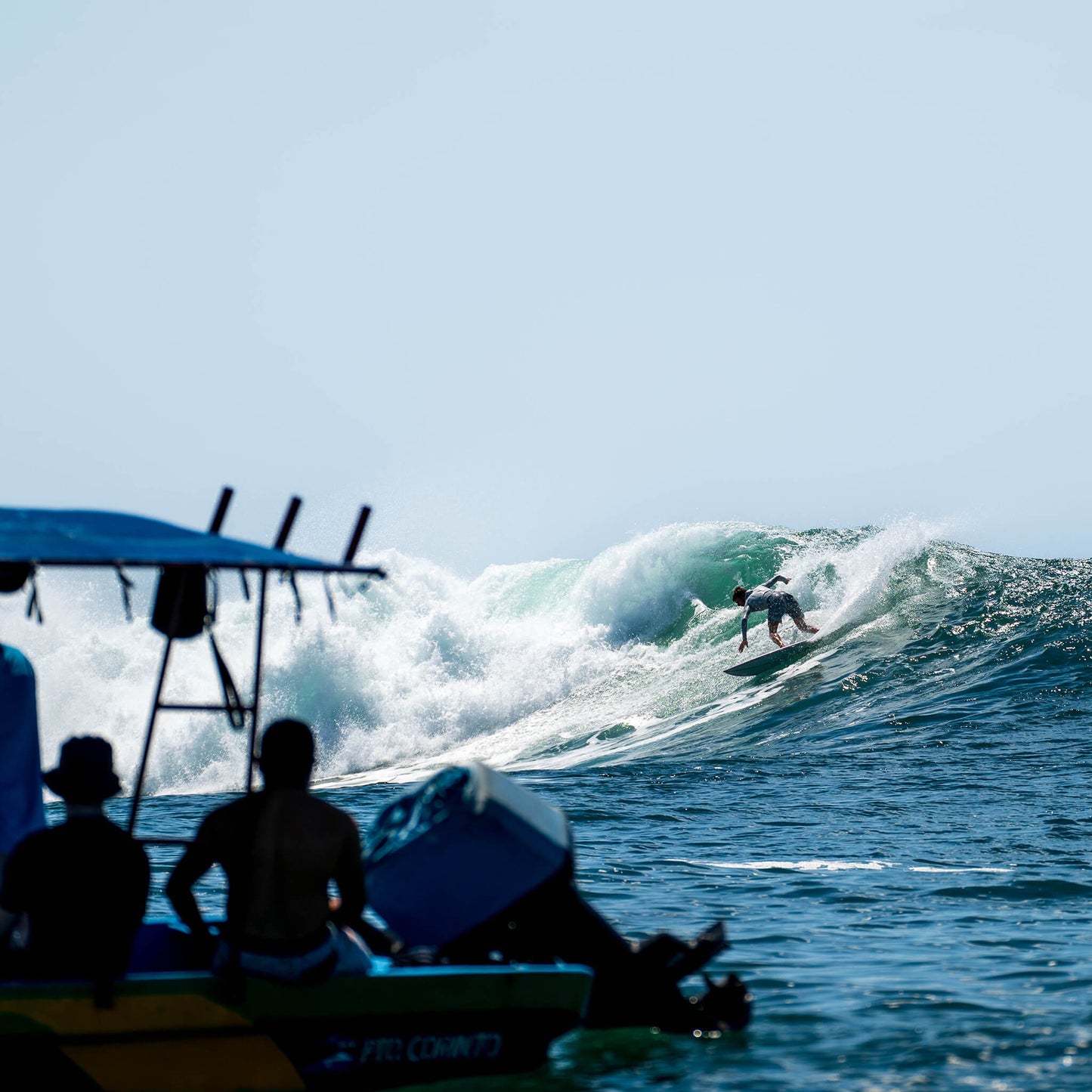 Surfer riding a wave with a boat in the foreground