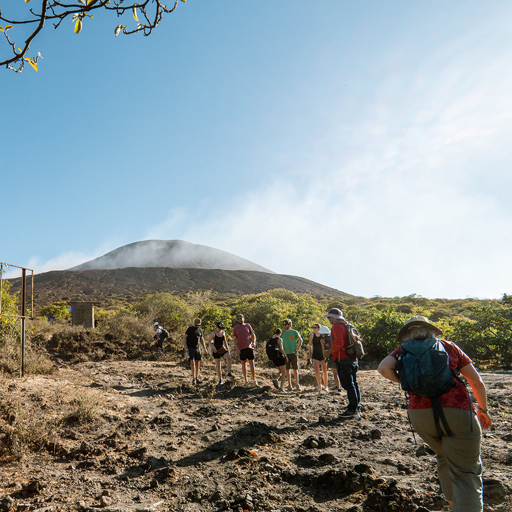 Group of people in the front ready to go hiking and in the background you can see the volcano Telica.